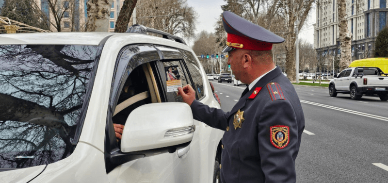 Police officer handing leaflet to driver