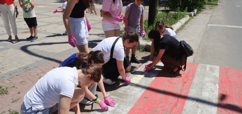 Volunteers using chalk to write safety messages on roads